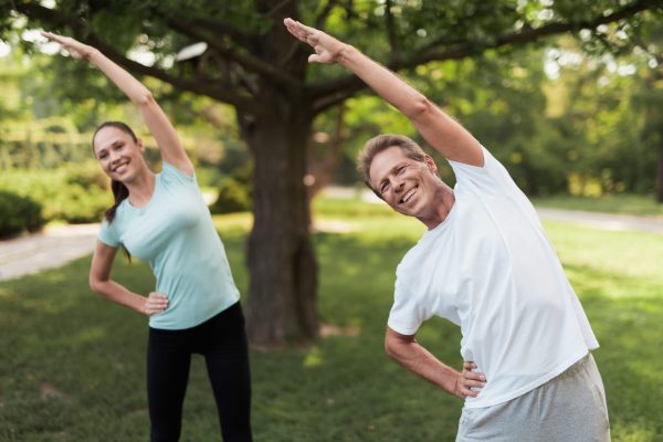 Couple,Doing,Exercises,In,The,Park.,Man,And,Woman,Doing Couple,Doing,Exercises,In,The,Park.,Man,And,Woman,Doing